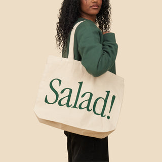 Person holding Salad! Collection canvas tote with "Salad!" across the side in kale.