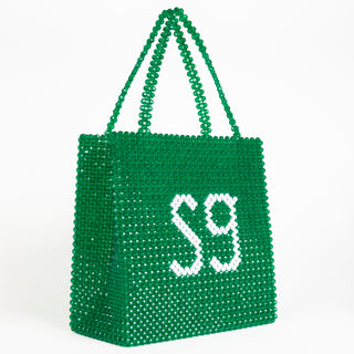 Angled front view of green Sweetgreen x Susan Alexandra beaded bag with "SG" in white beads.