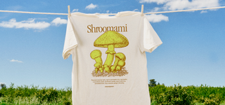 Back of Shroomami Tee with mushroom graphic hung on clothesline against a sunny field.