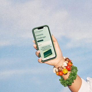 Person's hand with vegetable bracelets on their wrist holding up a mobile phone with the Sweetpass+ Membership open on their app.